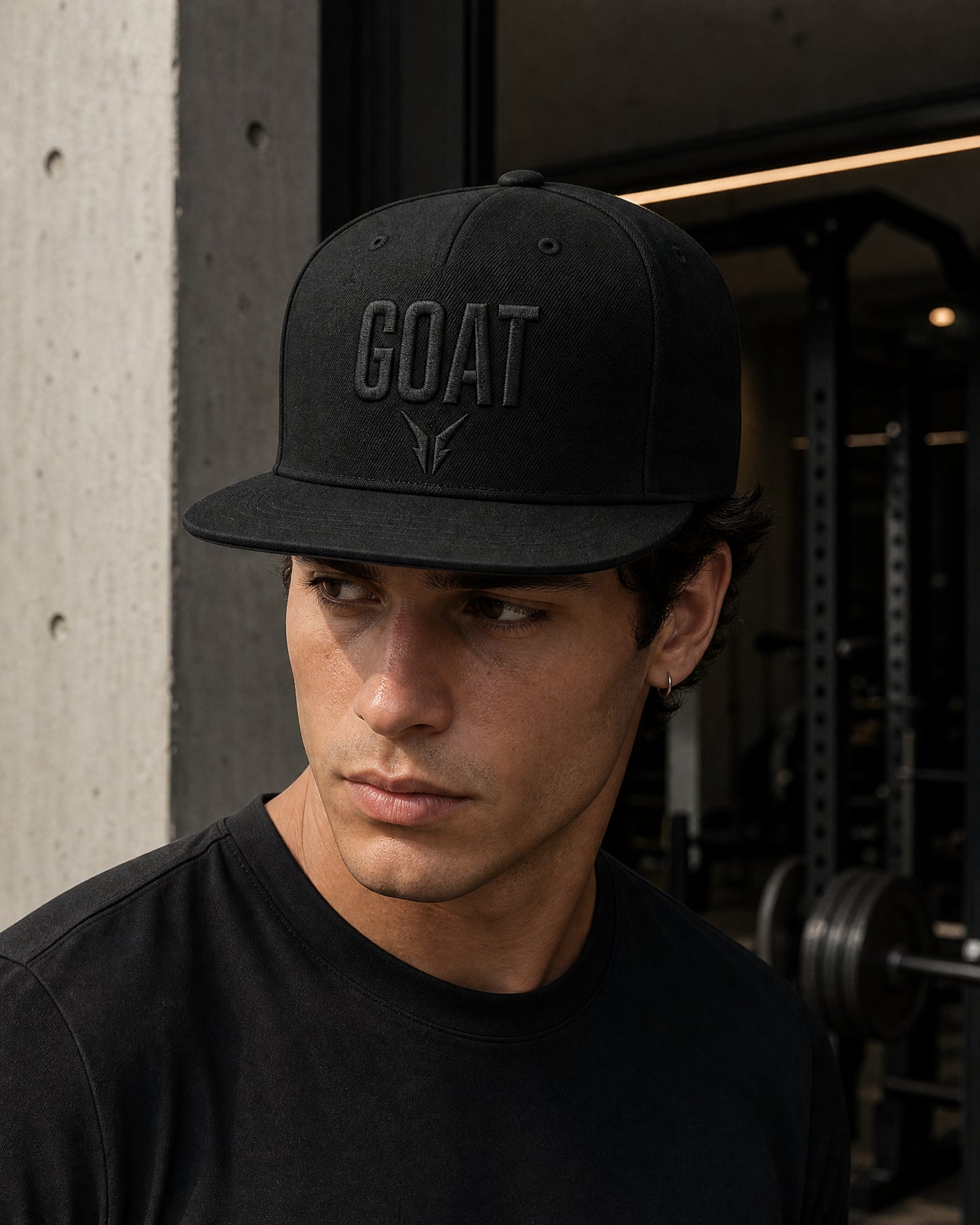 Gorra GOAT Total Black negra con bordado tonal, llevada por modelo en entorno de gimnasio
