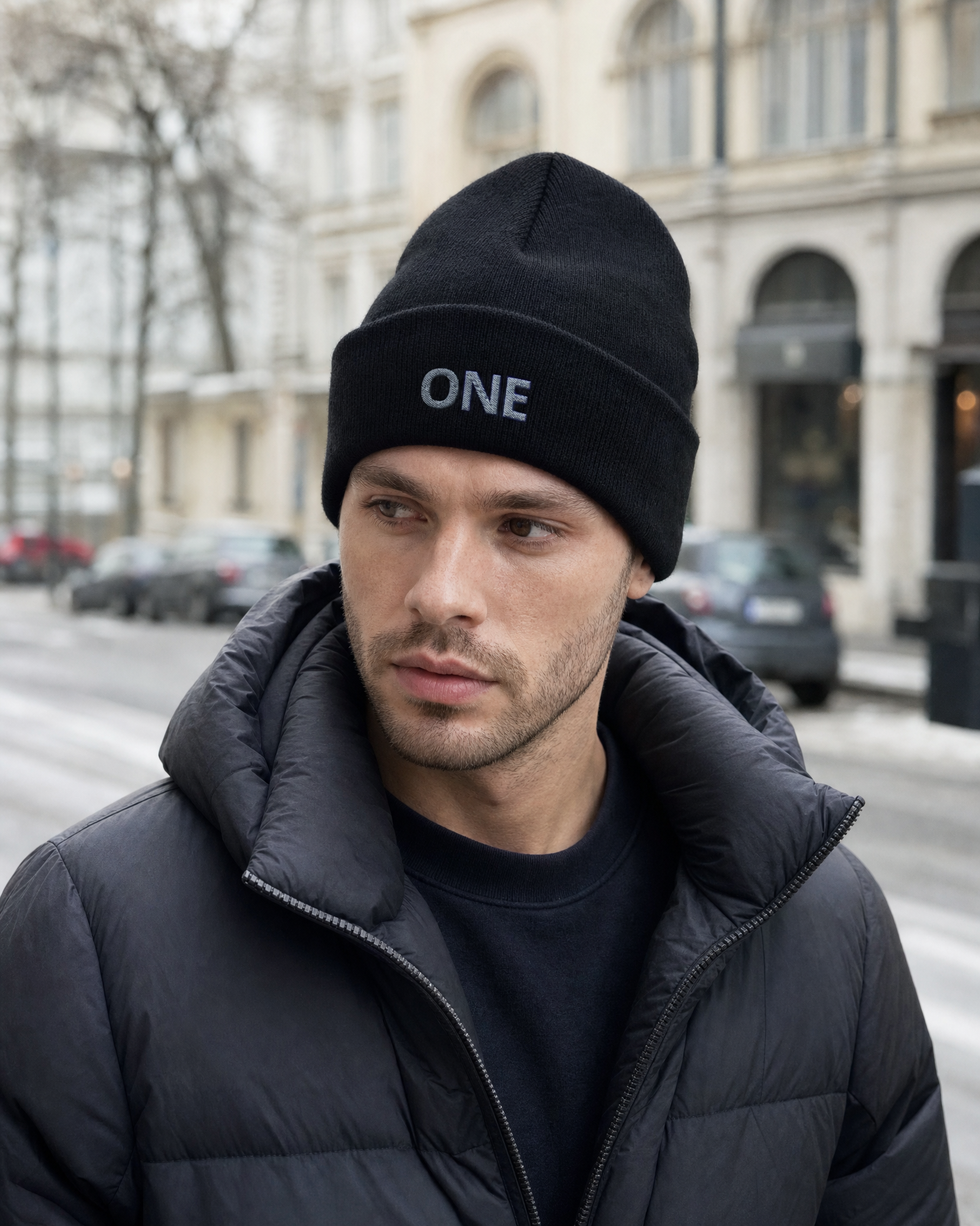 Gorro ONE Essential negro con bordado frontal, llevado por modelo en ciudad
